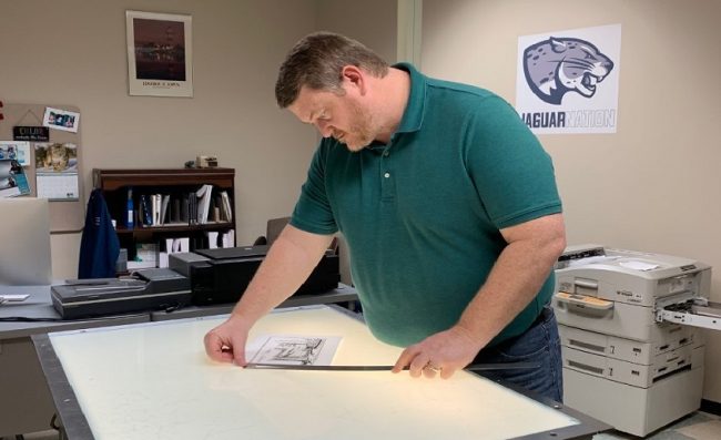 man in green shirt looks over file