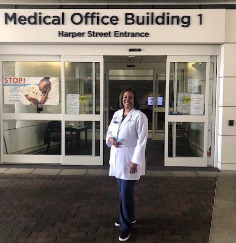 woman in white coat in front of medical building