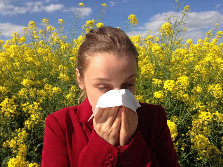 Woman sneezing into a tissue.