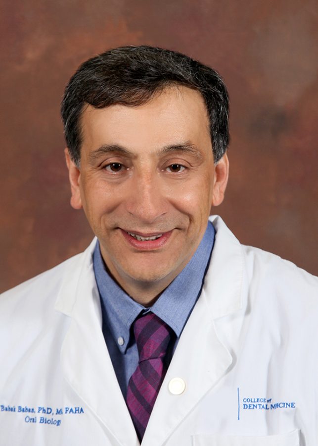 man in white doctor' coat smiling for a picture in front of a textured background