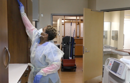 woman wearing PPE cleans room