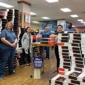 employees stand in bookstore among boxes