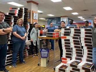 employees stand in bookstore among boxes