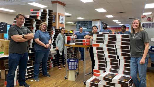 employees stand in bookstore among boxes