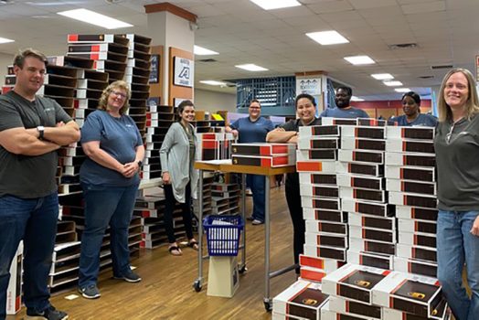 employees stand in bookstore among boxes