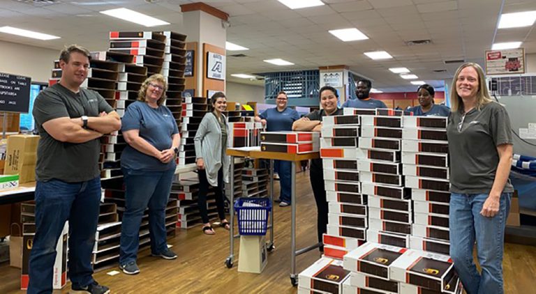 employees stand in bookstore among boxes
