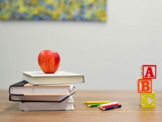 A photo of an apple on top of books next to letters.