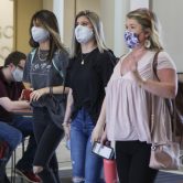 Three female college students walking wearing face masks.