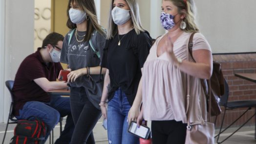 Three female college students walking wearing face masks.