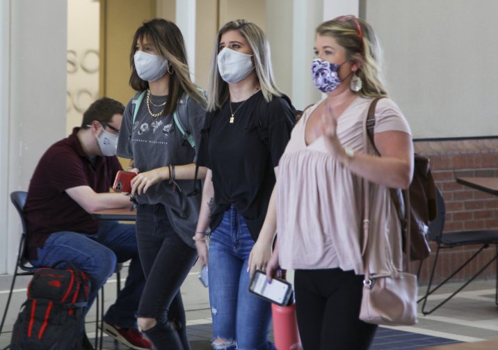 Three female college students walking wearing face masks.