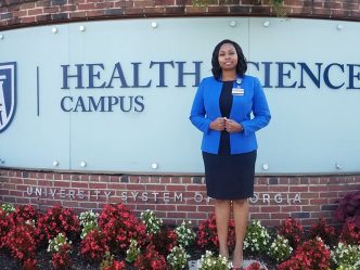 Woman stands in front of Health Sciences Campus sign