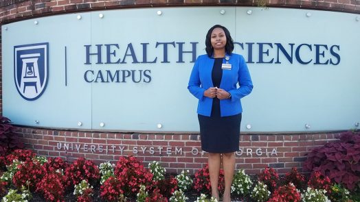Woman stands in front of Health Sciences Campus sign