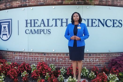 Woman stands in front of Health Sciences Campus sign