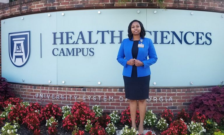Woman stands in front of Health Sciences Campus sign