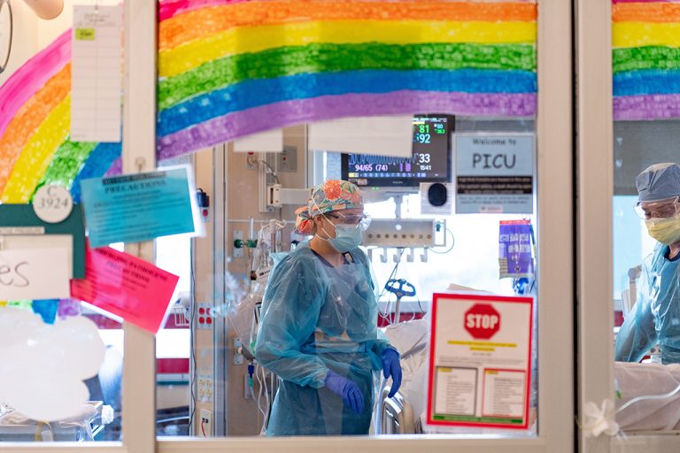 Health care workers under painted rainbow