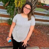 Teenage girl in a grey shirt and black pants.