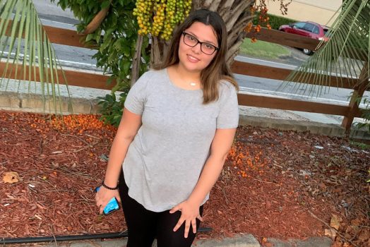 Teenage girl in a grey shirt and black pants.