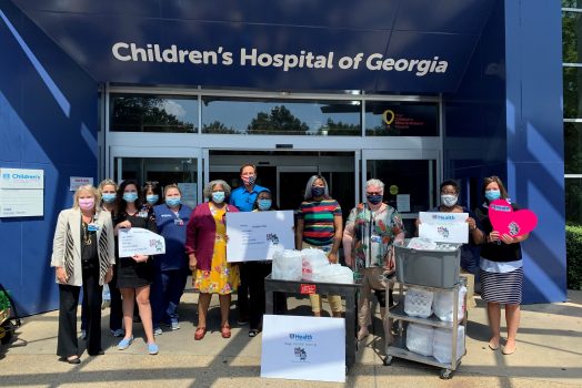 people in front of hospital entrance with signs and carts of food