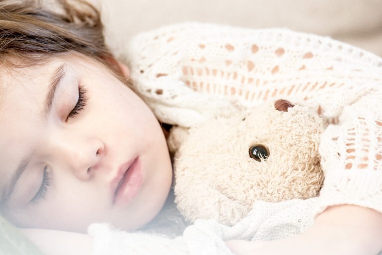 Girl napping with a bear.