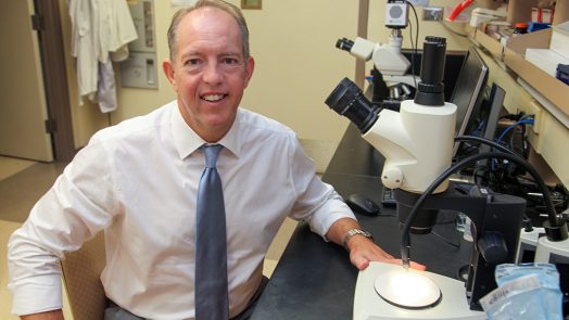 Man at microscope smiling