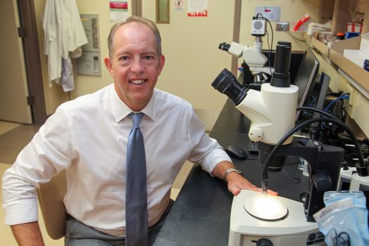 Man at microscope smiling