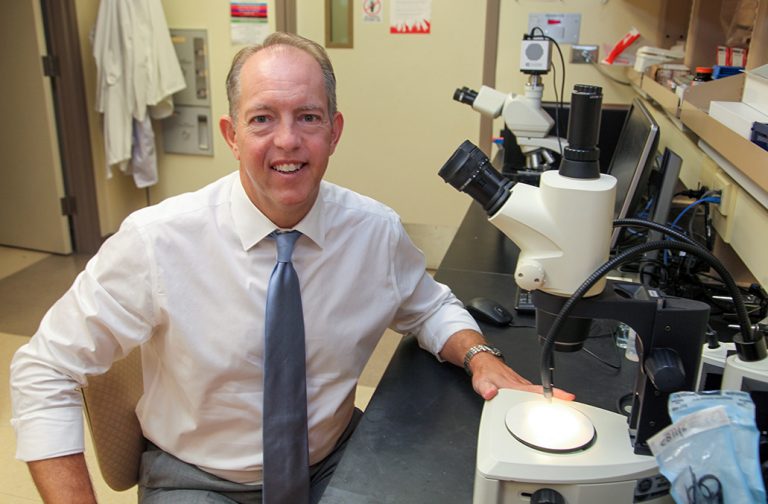 Man at microscope smiling