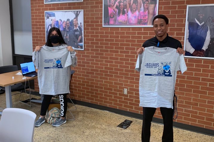 two students hold up grey Jaguars Mask Up T-shirt