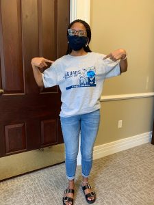 Woman in glasses and a mask poses wearing grey "Jaguars Mask Up" t-shirt