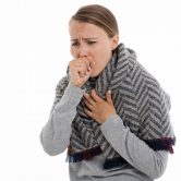 Woman coughing into her hand.