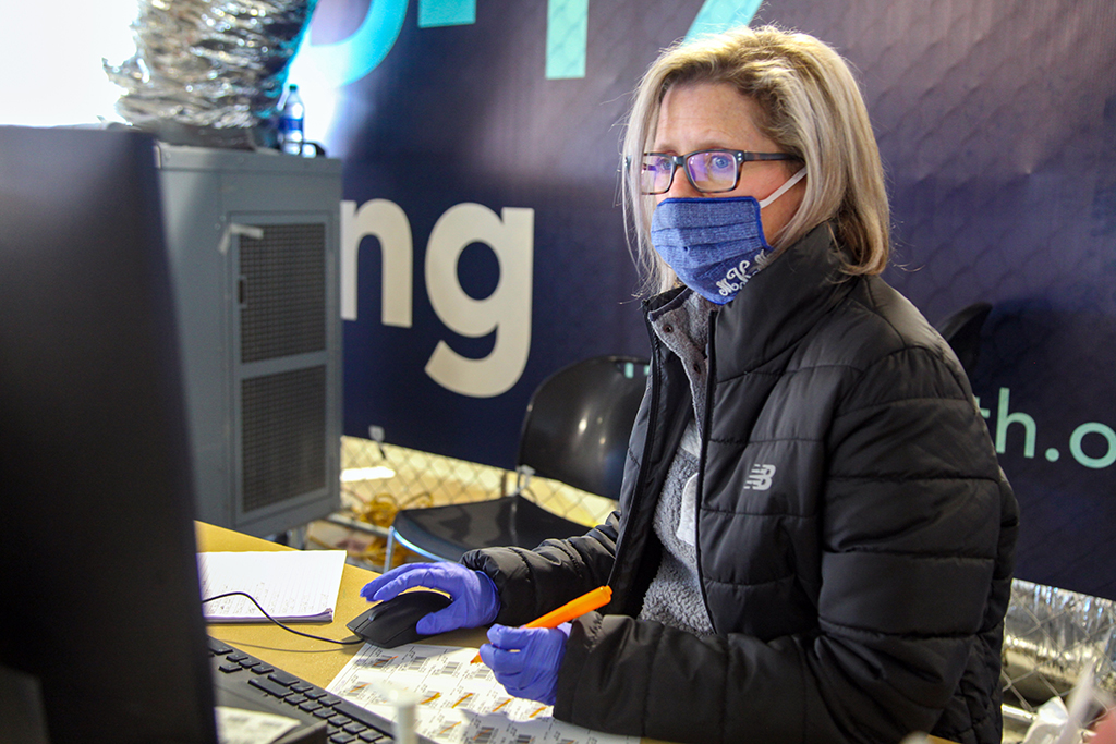 Woman in jacket and mask at computer