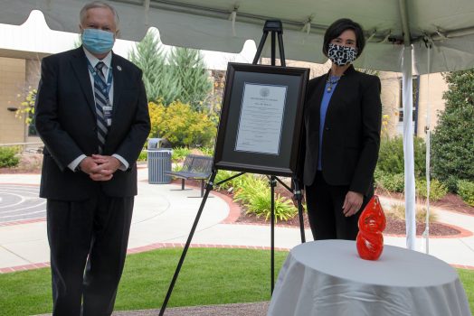 man and woman stand by award and frame