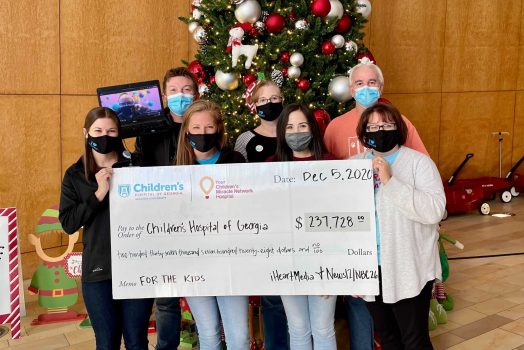 people with giant check in front of Christmas tree