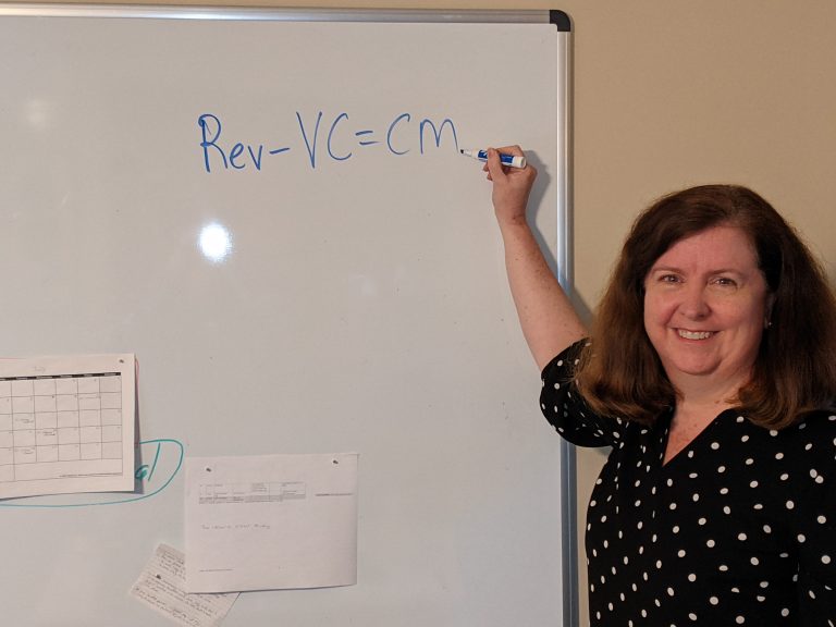 A woman writing on a dry erase board.