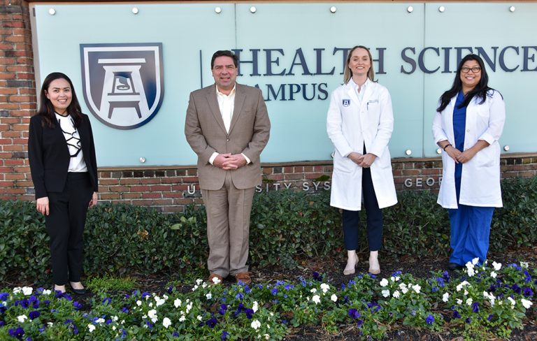 Three women, one man standing in front of a sign