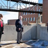 woman, two men stand six feet apart
