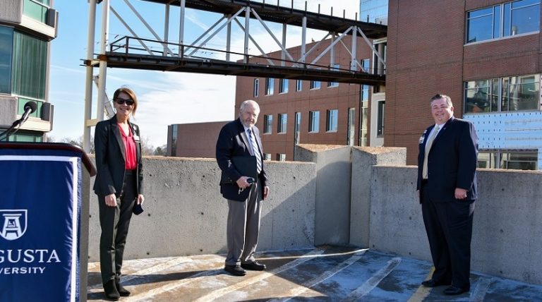 woman, two men stand six feet apart