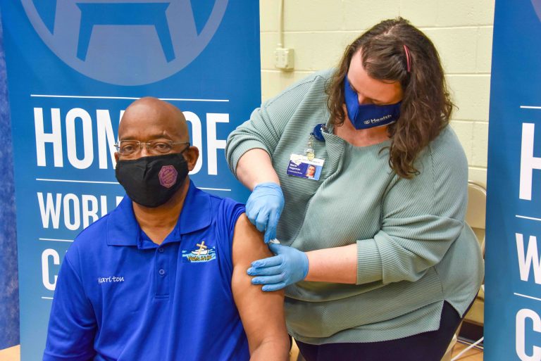 woman places bandage on man's arm