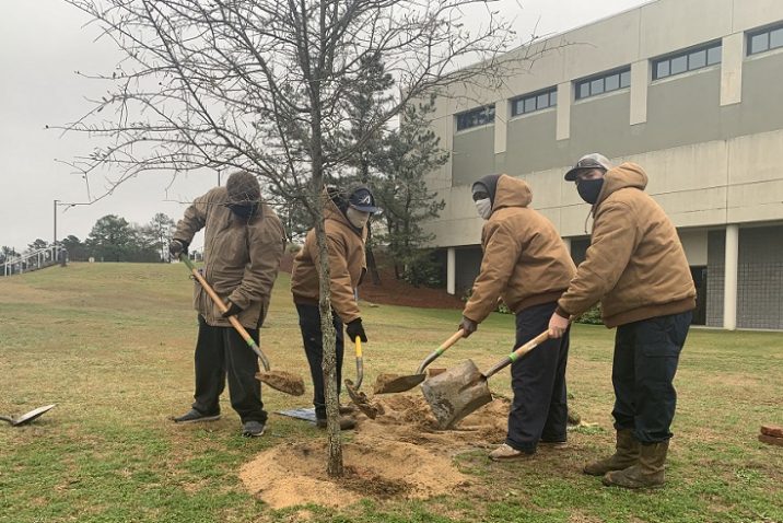 4 men with shovels scoop dirt