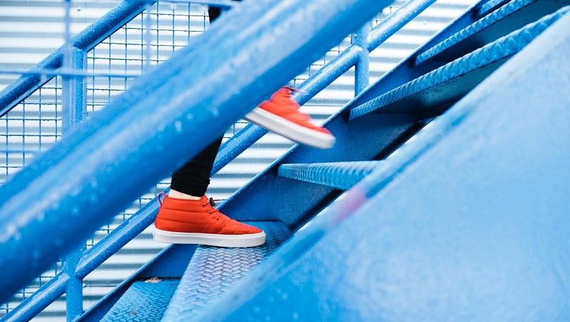 red sneakers going up blue stairway