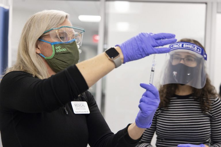 woman draws vaccine as woman watches