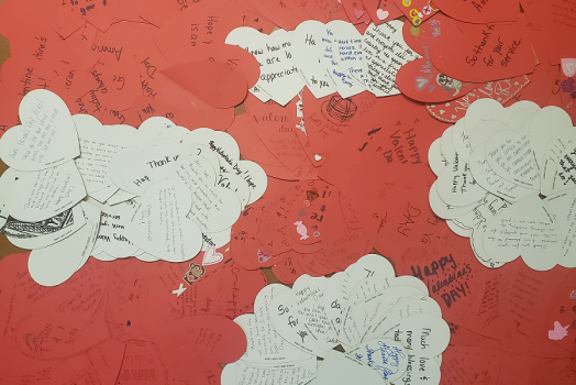 pile of red and white paper hearts with notes written on them