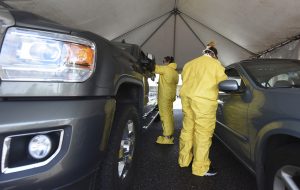 Two workers in PPE testing patients inside cars