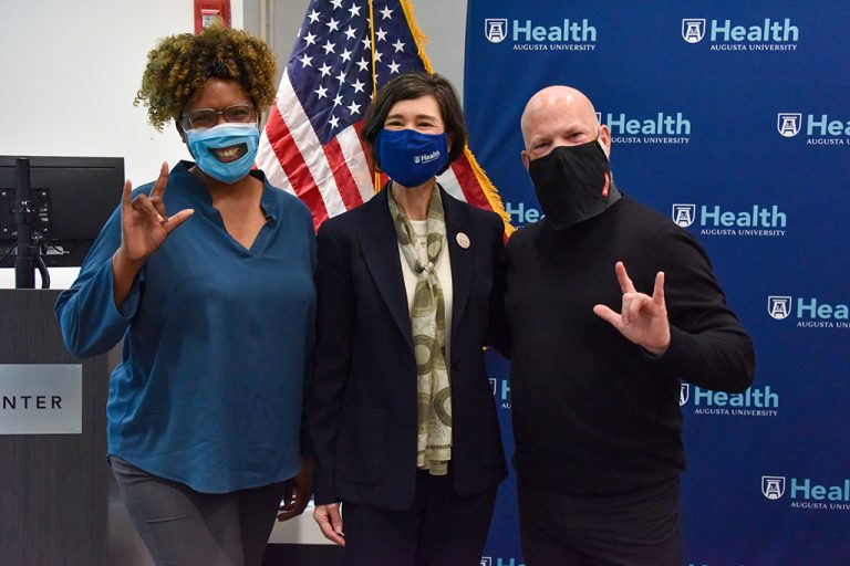 Two women and a man in masks