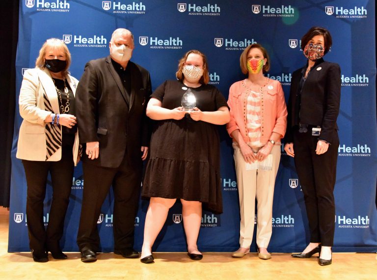 woman holds award in group with three other women and man