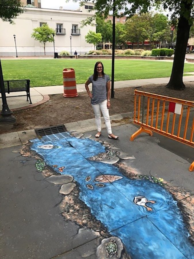 Woman stands next to mural