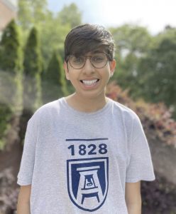 a male student wearing classes and a grey Augusta University T-shirt smiles for a photo