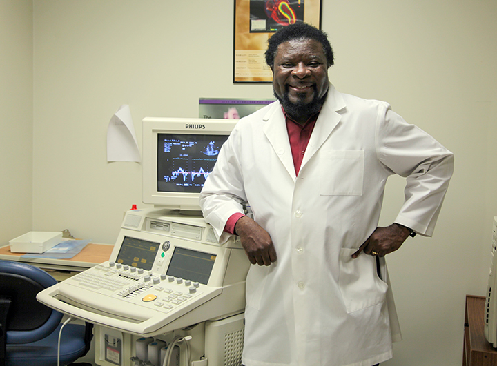 Dr. Gaston Kapuku, in white lab coat, stands in front of lab equipment