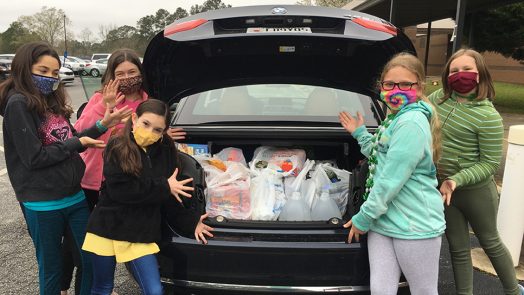 Students with a trunk full of groceries in bags