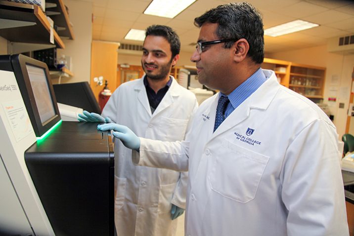 Dr. Ravindra Kolhe stands in the forefront of a lab with his research associate looking on