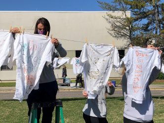 female student hangs up shirt on clothesline